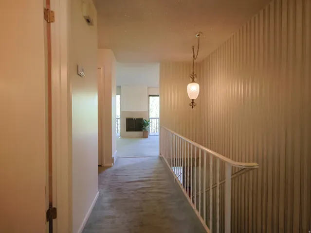 Hallway with striped wall covering and a pendant light fixture