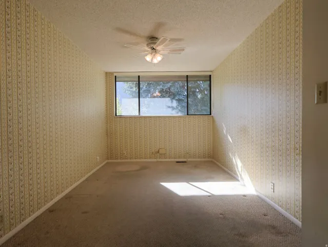 Recessed window, textured wallpaper, ceiling fan with light fixture, carpeted flooring, wall-mounted outlets