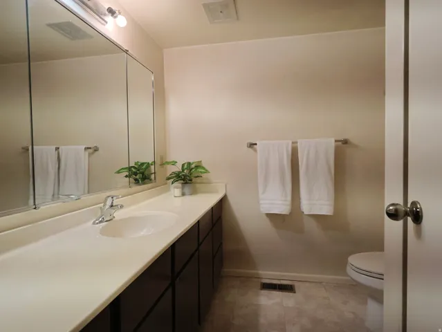 Bathroom featuring a long vanity with an integrated sink, dark wood-finish cabinetry, a large mirrored medicine cabinet, and a chrome faucet