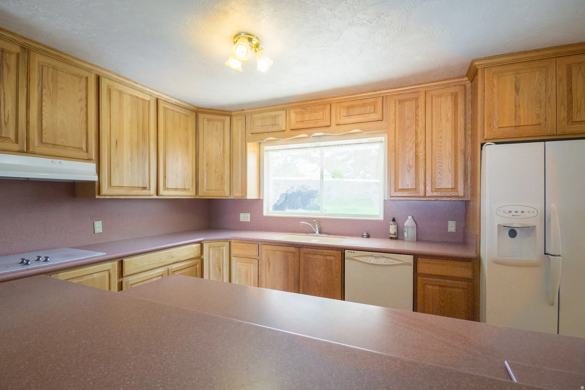 Kitchen featuring extensive wood cabinetry, solid surface countertops, and a built-in dishwasher
