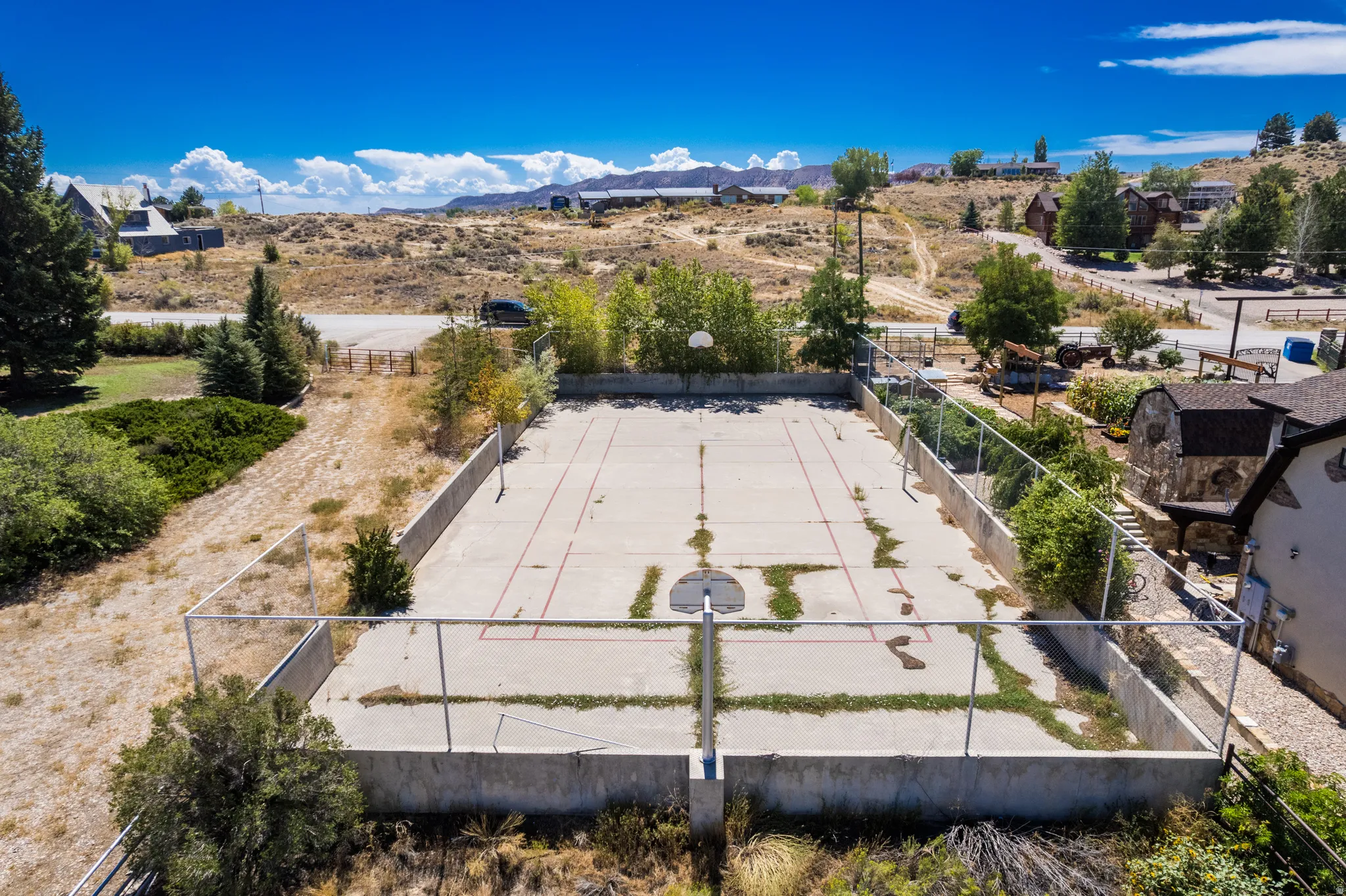 Concrete sports court with perimeter fencing, two basketball hoops, and painted court lines