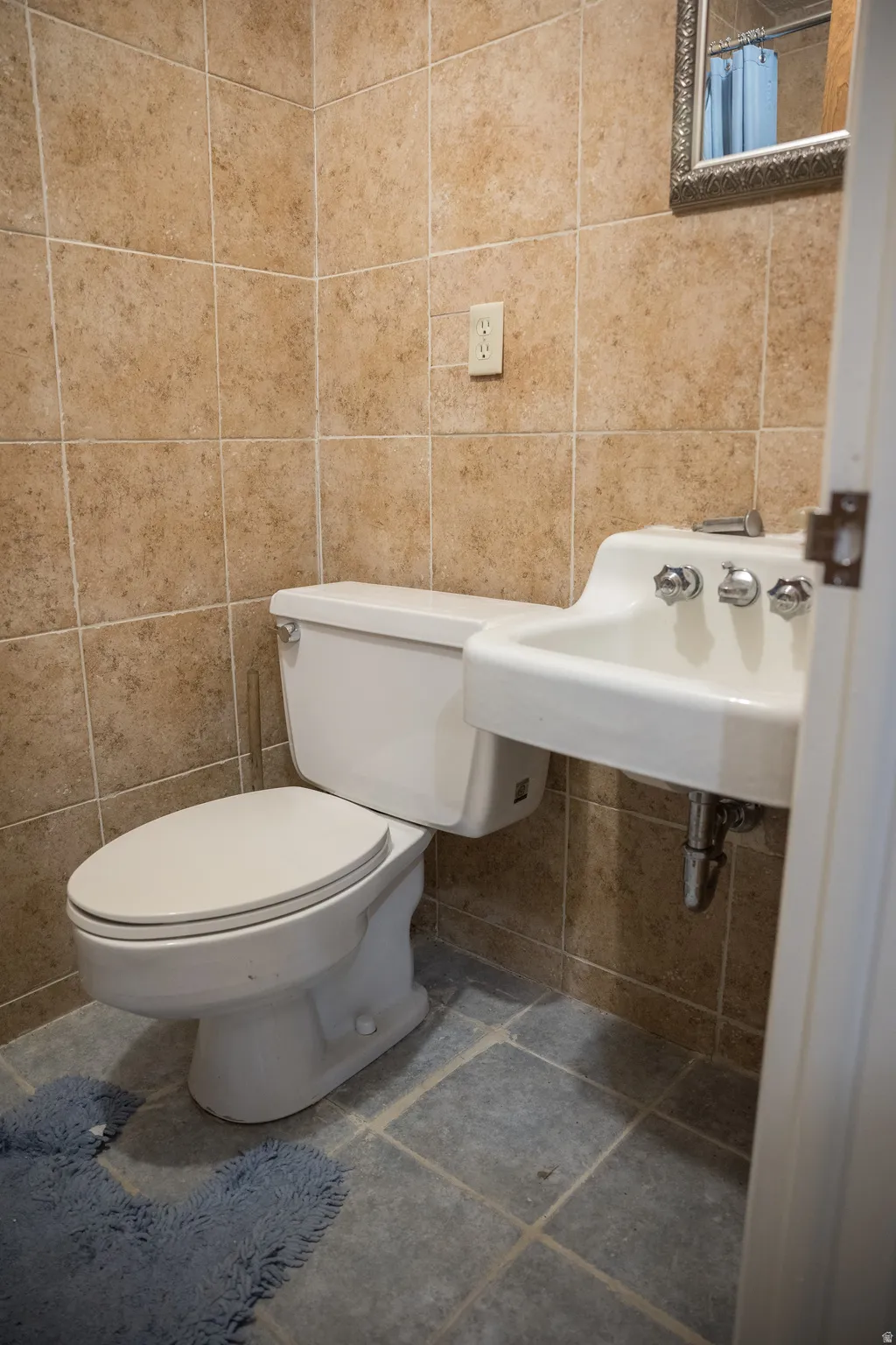 Wall-mounted sink with chrome fixtures and a white toilet