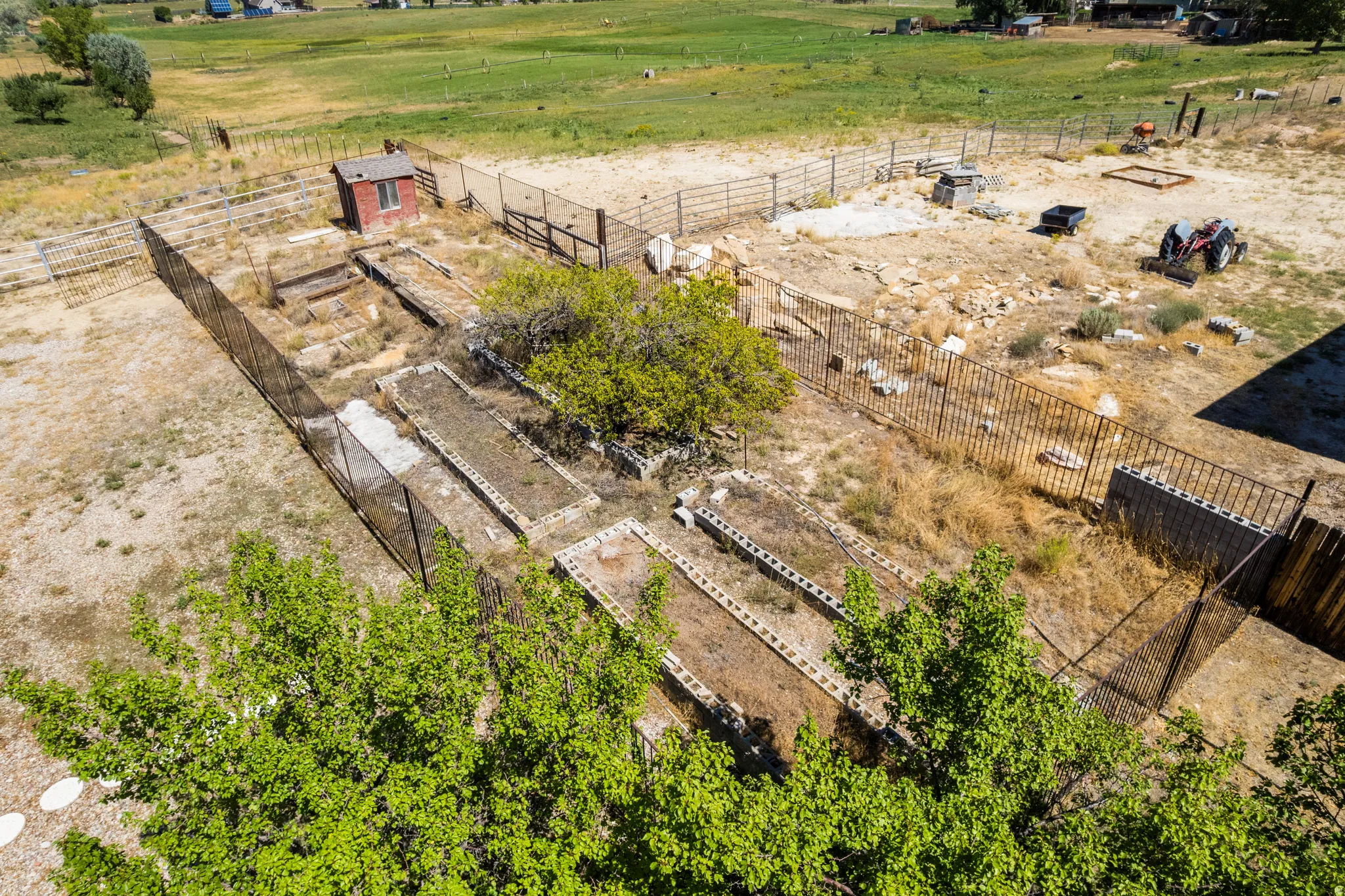 Extensive fenced land parcel with established garden beds, a storage shed, and open terrain