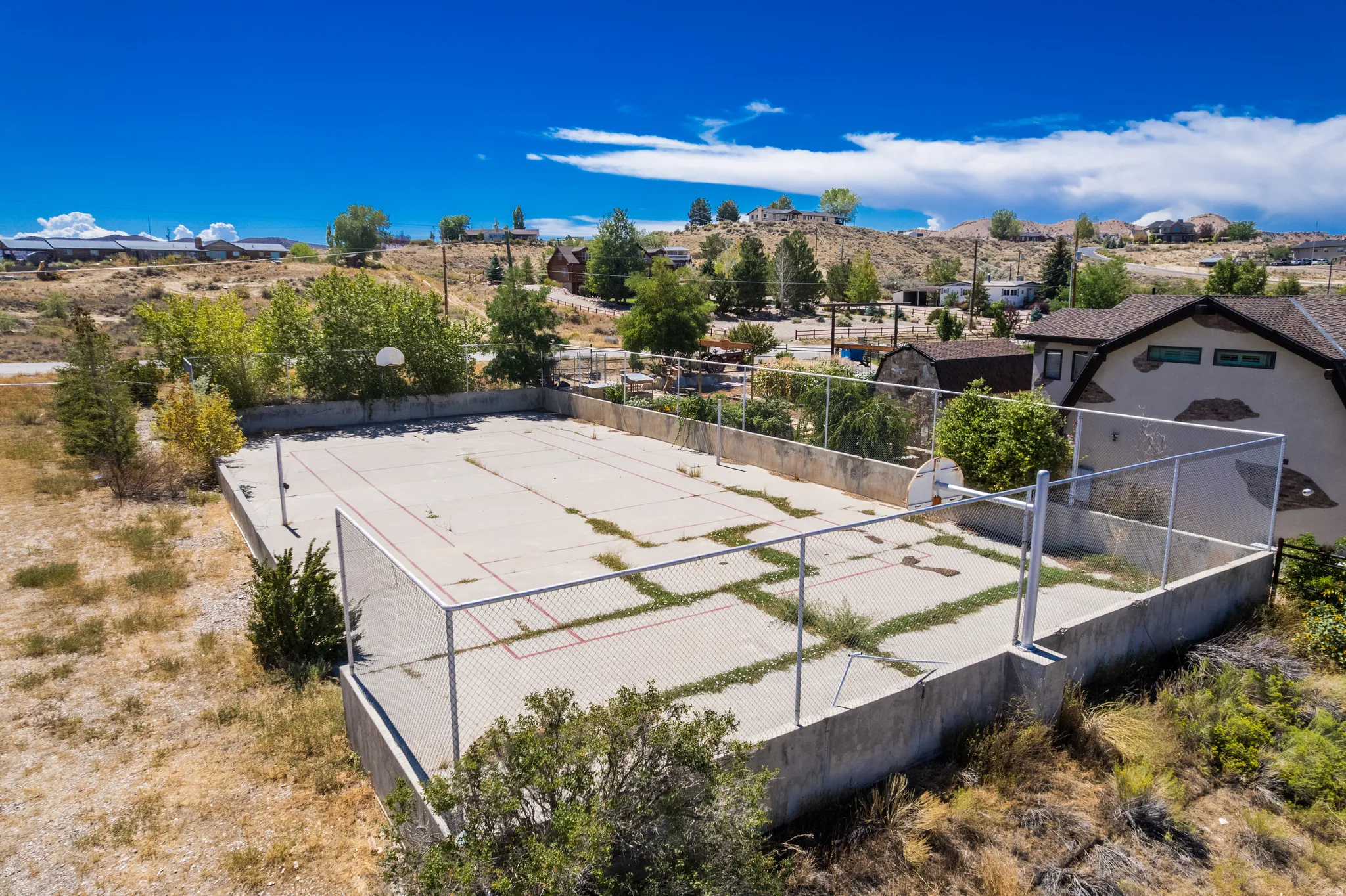 Concrete multi-sport court with chain link fencing and basketball hoop
