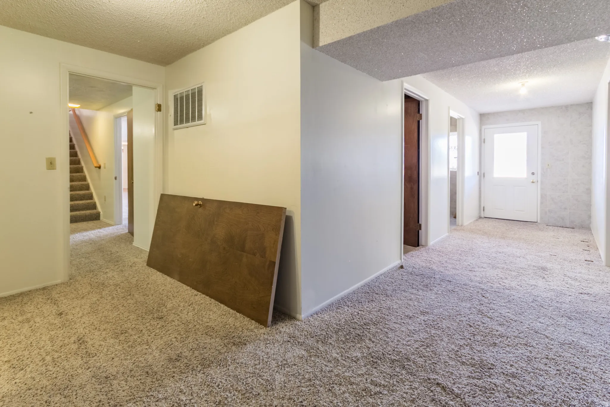 Staircase with carpeted treads and a wood handrail