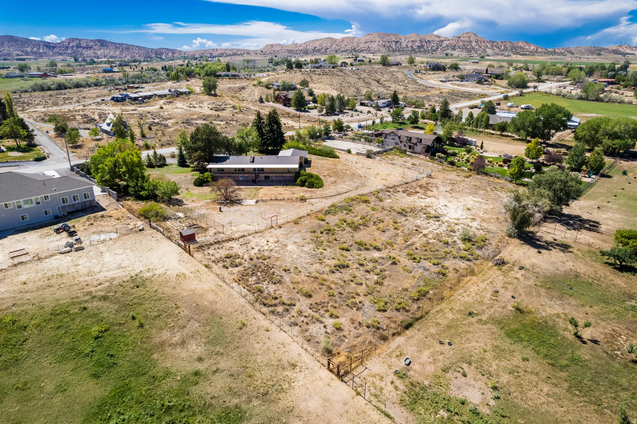 Expansive property featuring a large open lot, surrounding natural landscaping, and distant mountain backdrops