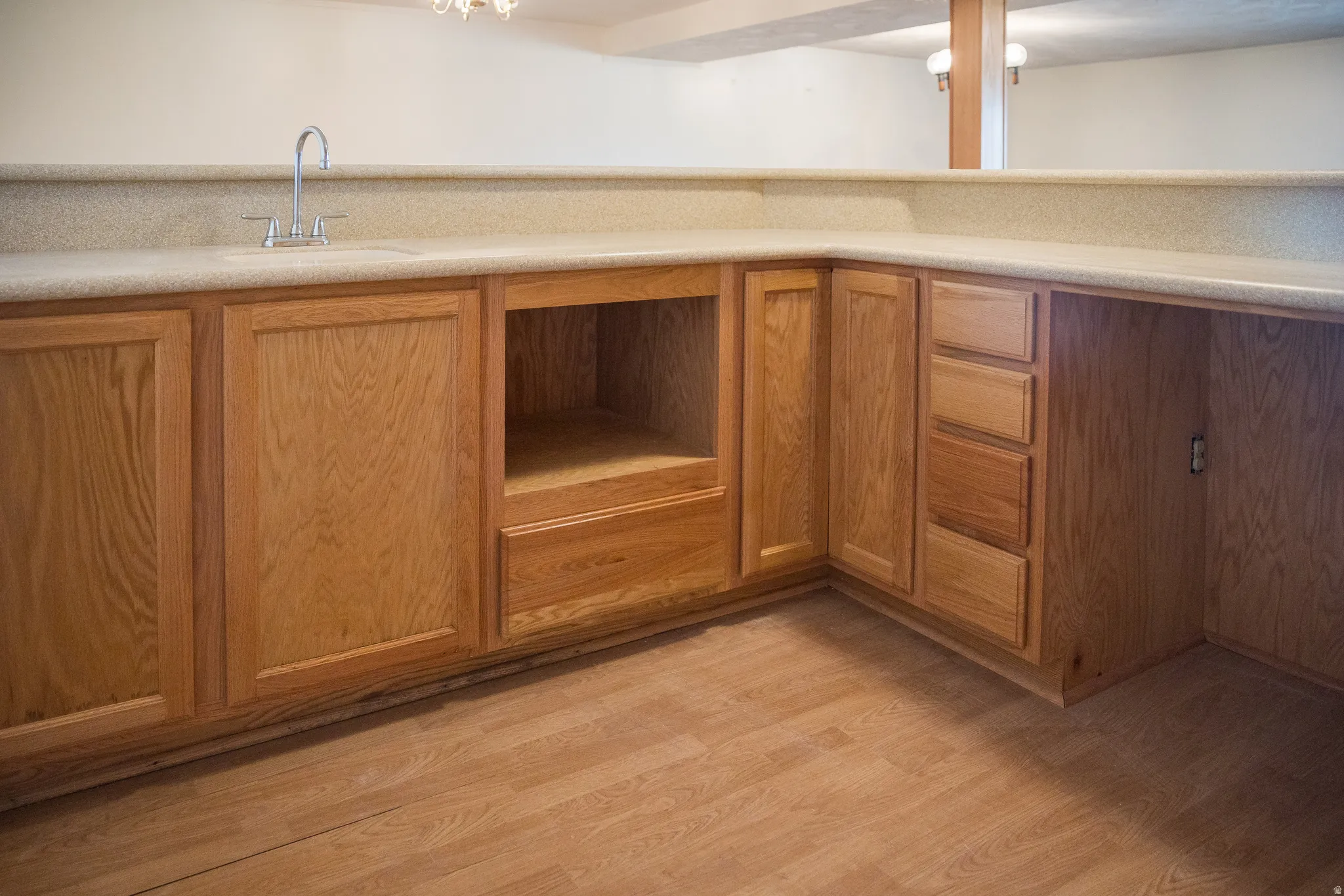 Built-in cabinetry with wood-finish doors and drawers, a countertop with an integrated sink, and wood-finish flooring