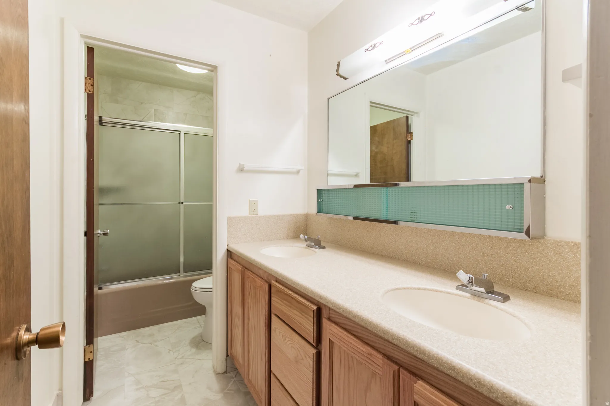 Dual vanity with integrated sinks, wood-finish cabinetry, and a full-width mirror