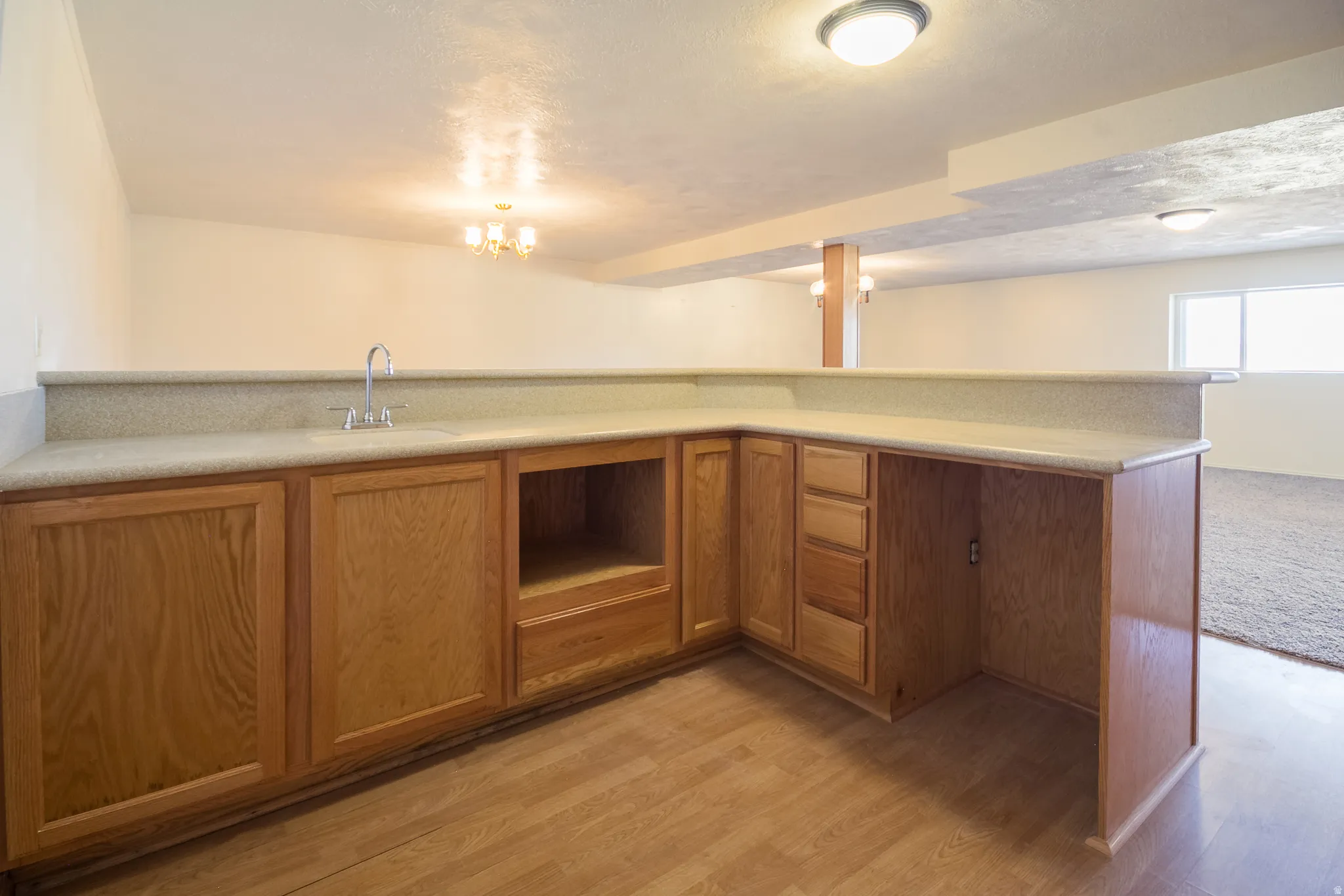 Built-in bar with wood-finish cabinetry, integrated sink, and light-toned countertop