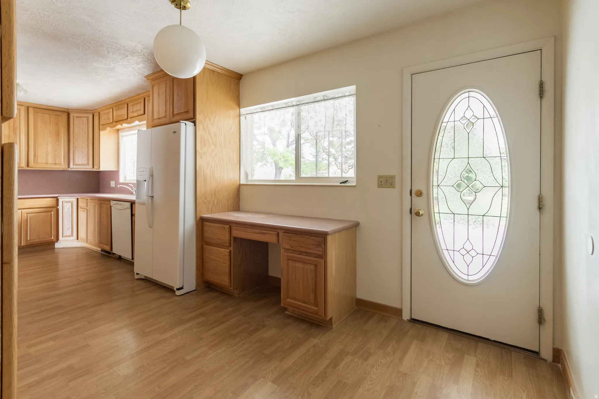 Kitchen with wood-finish flooring, light wood cabinetry, and white appliances