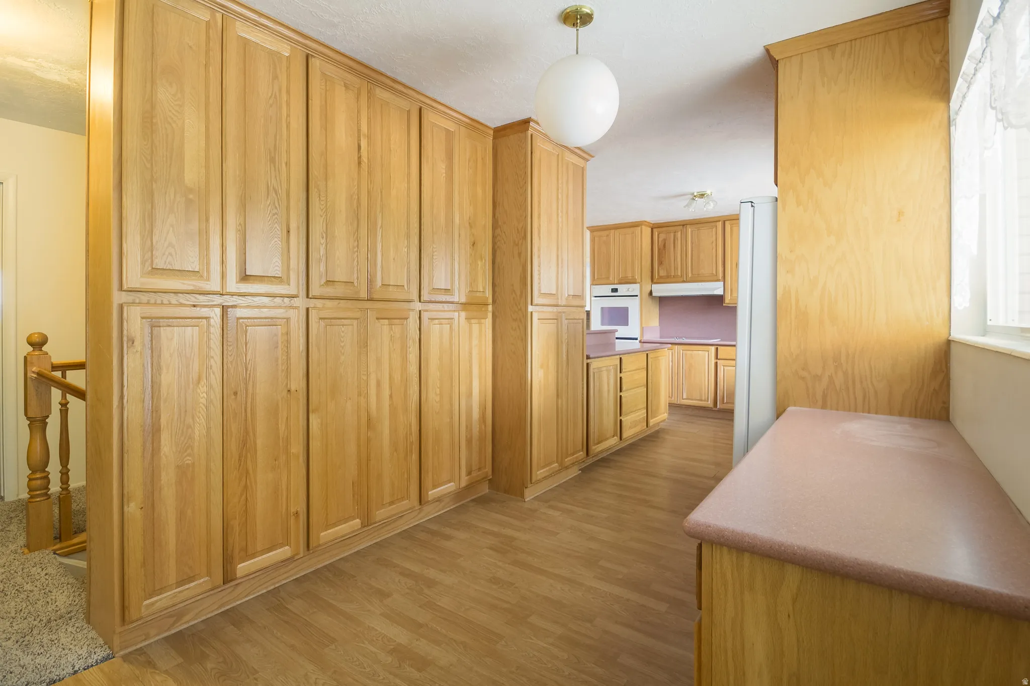Extensive wood-finish cabinetry, wood-finish flooring, built-in oven, and a wood-finish railing
