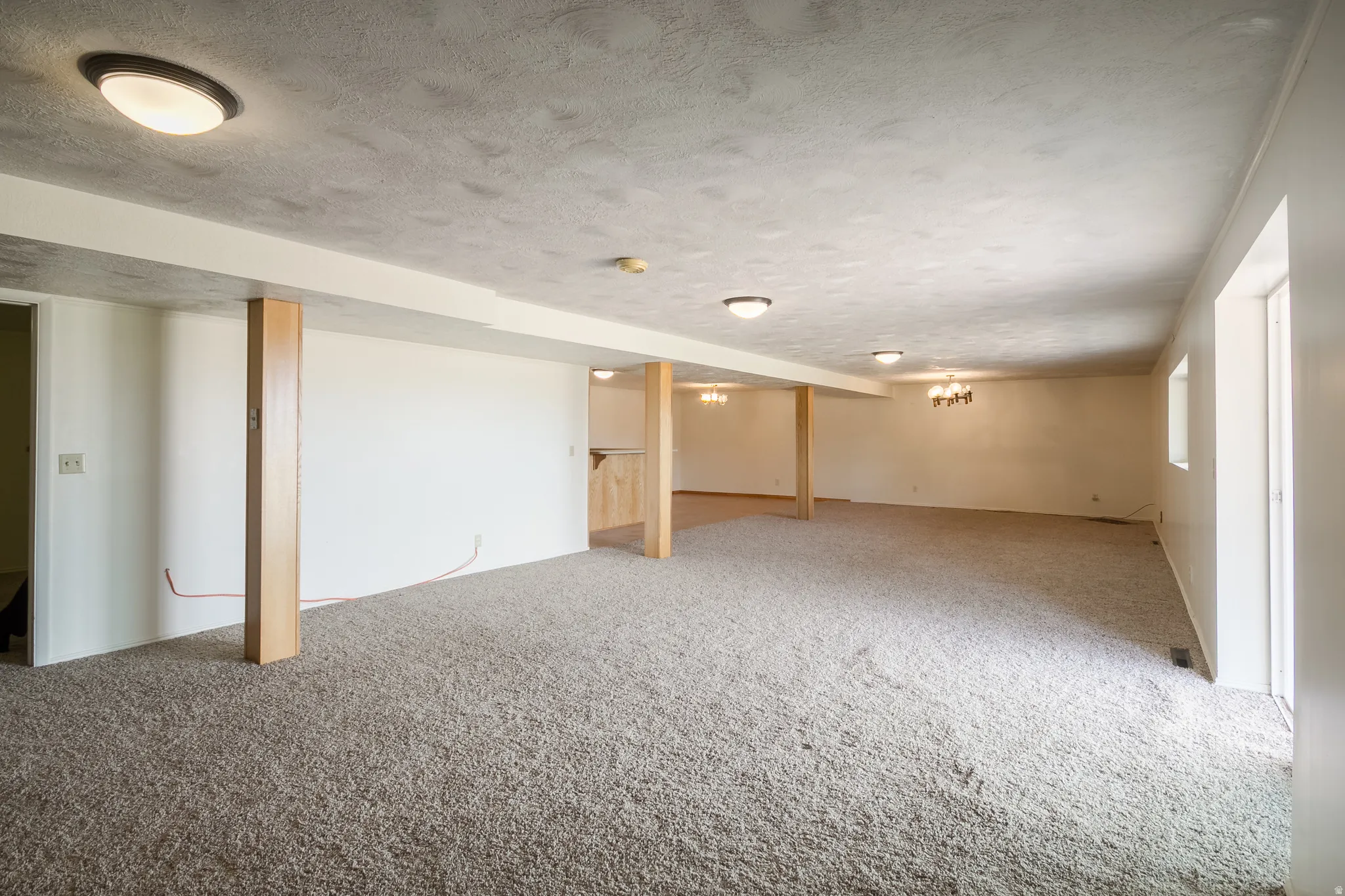 Expansive carpeted area with recessed lighting and exposed structural columns