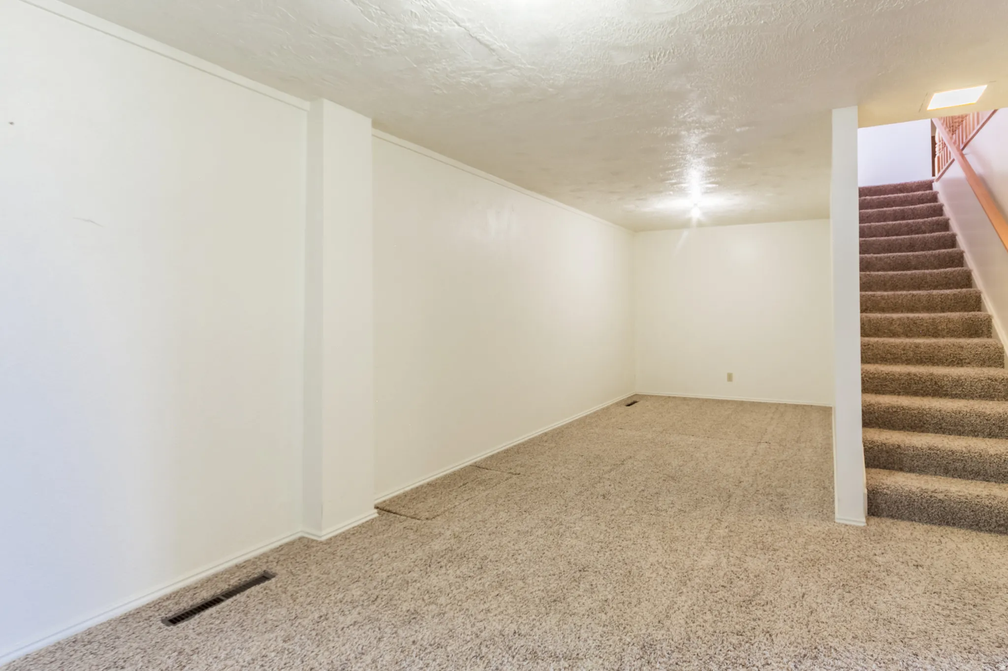 Carpeted room with white painted walls and a textured ceiling