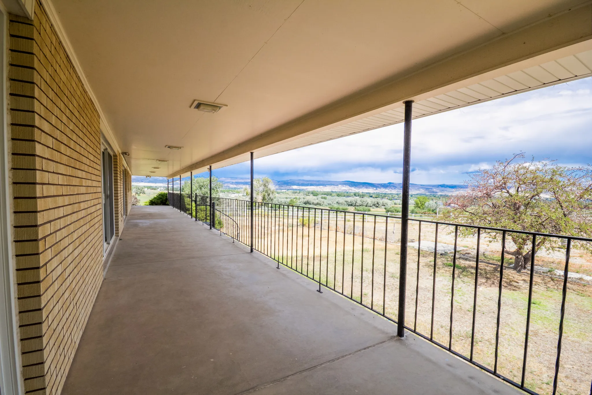 Expansive concrete balcony with a black metal railing and supporting columns