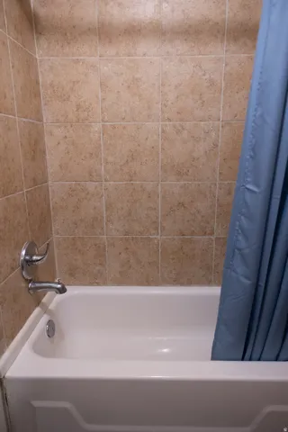 White bathtub with chrome fixtures and tiled surround