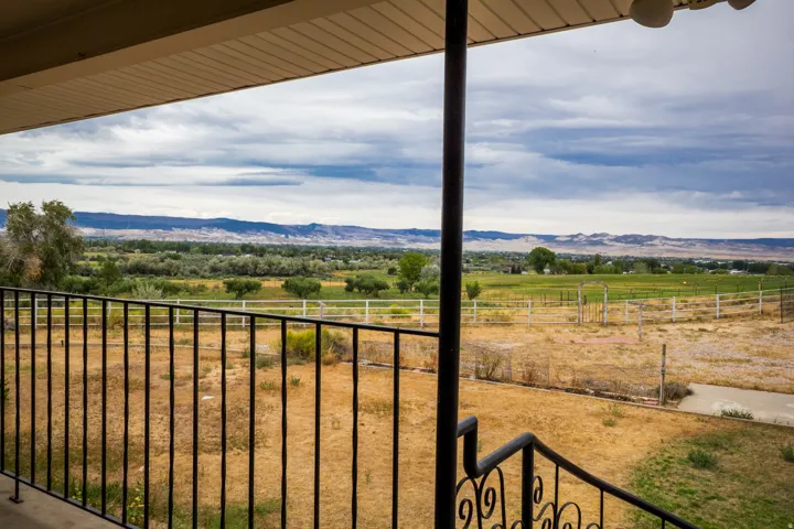 Expansive outdoor balcony with wrought iron railing overlooking a vast landscape with distant mountains