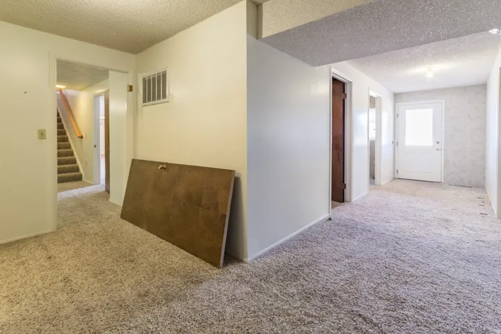 Staircase with carpeted treads and a wood handrail
