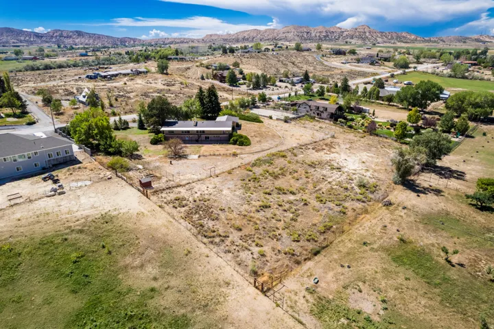 Expansive property featuring a large open lot, surrounding natural landscaping, and distant mountain backdrops