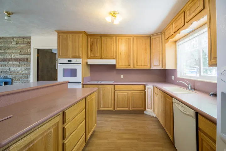 Kitchen featuring wood-finish flooring, wood cabinetry, a built-in oven, and dual basin sink