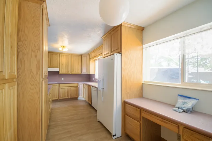 Kitchen featuring extensive wood cabinetry, laminate countertops, wood-finish flooring, a built-in desk area, and an integrated ceiling light fixture