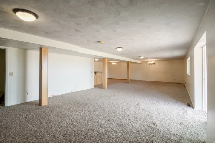 Expansive carpeted area with recessed lighting and exposed structural columns