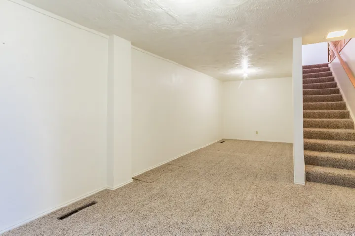 Carpeted room with white painted walls and a textured ceiling
