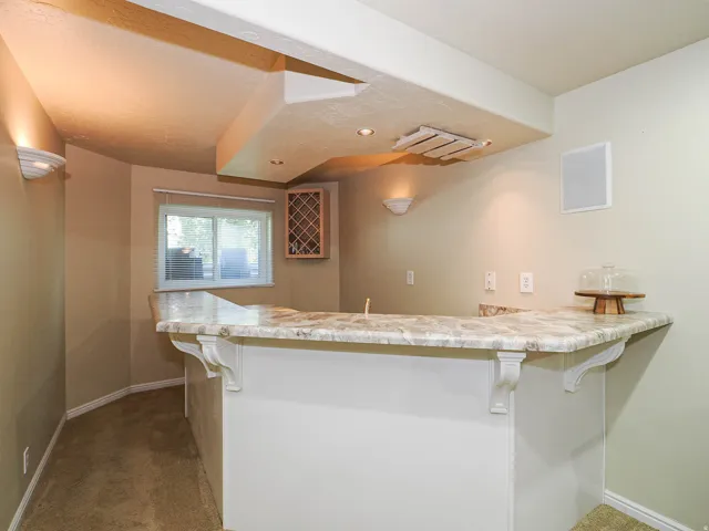 Built-in bar with a stone-finish countertop, decorative corbels, recessed lighting, and an integrated wine rack