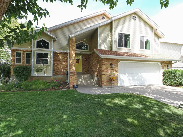Brick and siding exterior, arched window accents, attached two-car garage, concrete driveway, and front lawn