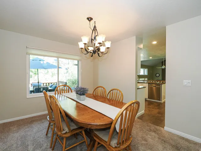Recessed lighting, sliding glass door, and a multi-arm chandelier illuminate this space, featuring carpet flooring
