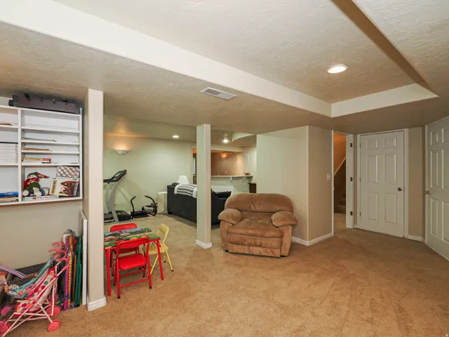 Carpeted living space with recessed lighting, built-in shelving, and a white paneled door