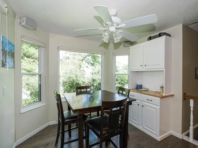 Bay window with multiple panes, wood-finish flooring, built-in white cabinetry with a wood countertop, and a ceiling fan with integrated lighting