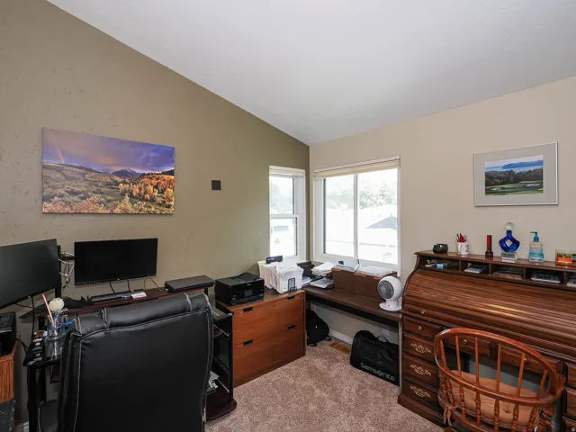 Vaulted ceiling with textured finish, carpeted flooring, and two windows providing exterior exposure