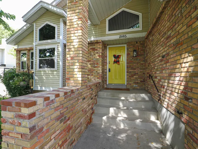 Brick exterior with complementary siding, prominent entry steps, a contrasting entry door, and an arched window accent