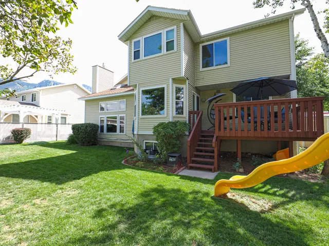 Expansive green lawn with mature trees and a multi-level wood deck