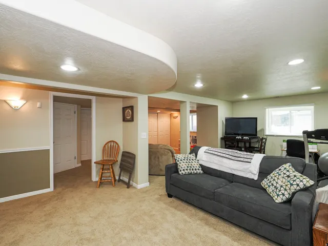 Carpeted living area with recessed lighting, a built-in wall sconce, white trim, and a window