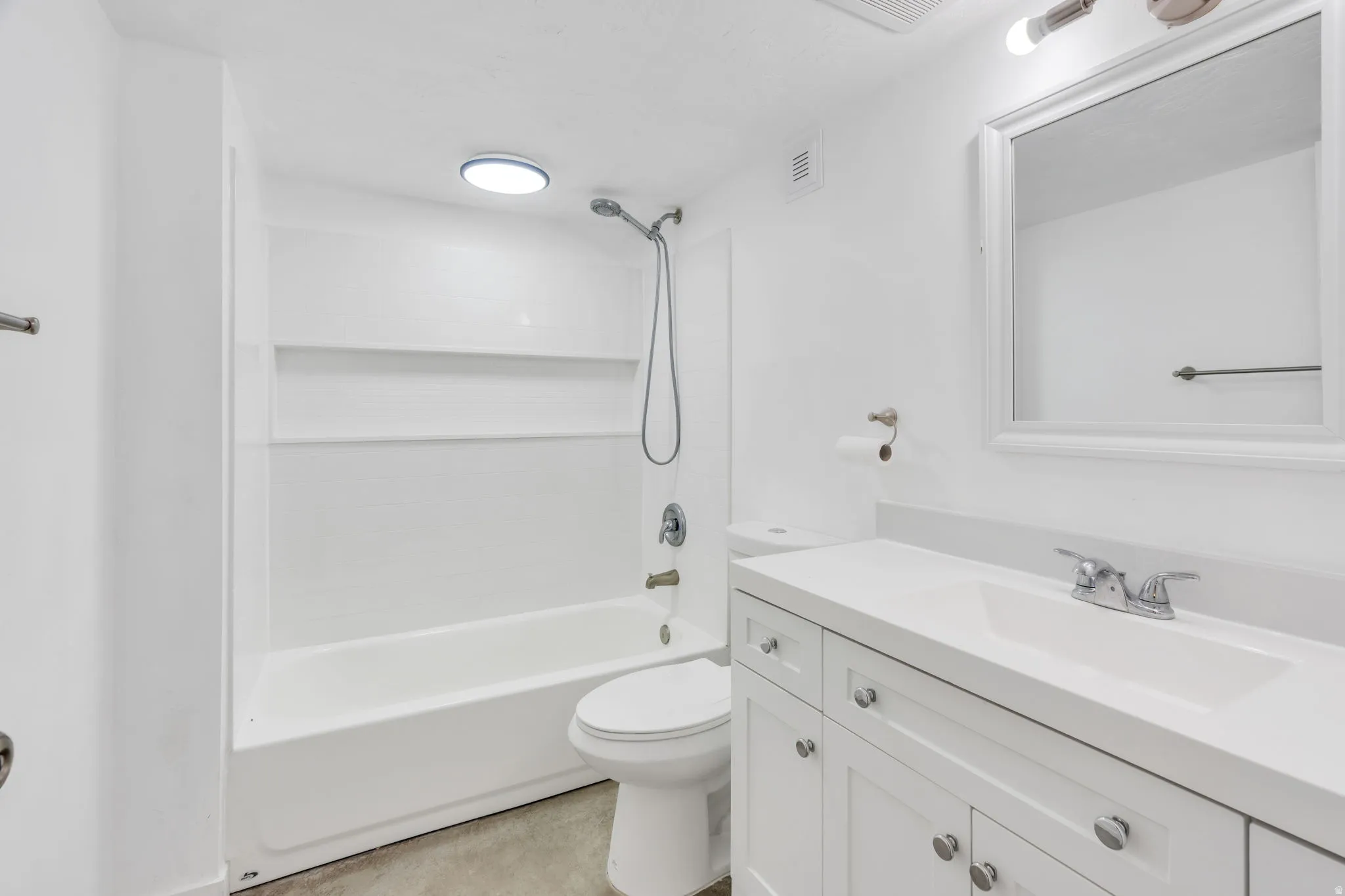 White vanity with a single basin sink, chrome faucet, and framed mirror