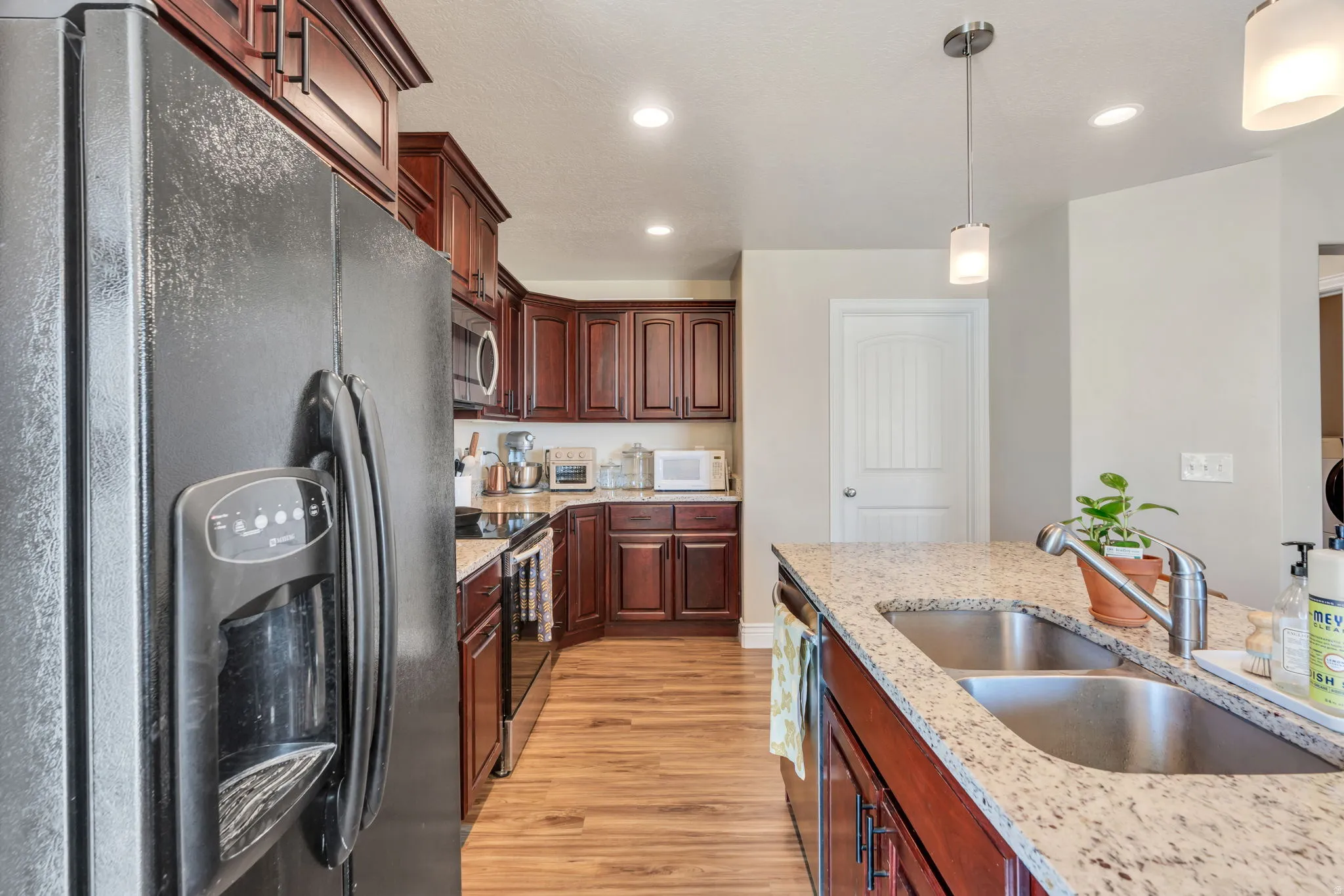 Kitchen featuring wood-finish flooring, dark wood cabinetry, and granite countertops