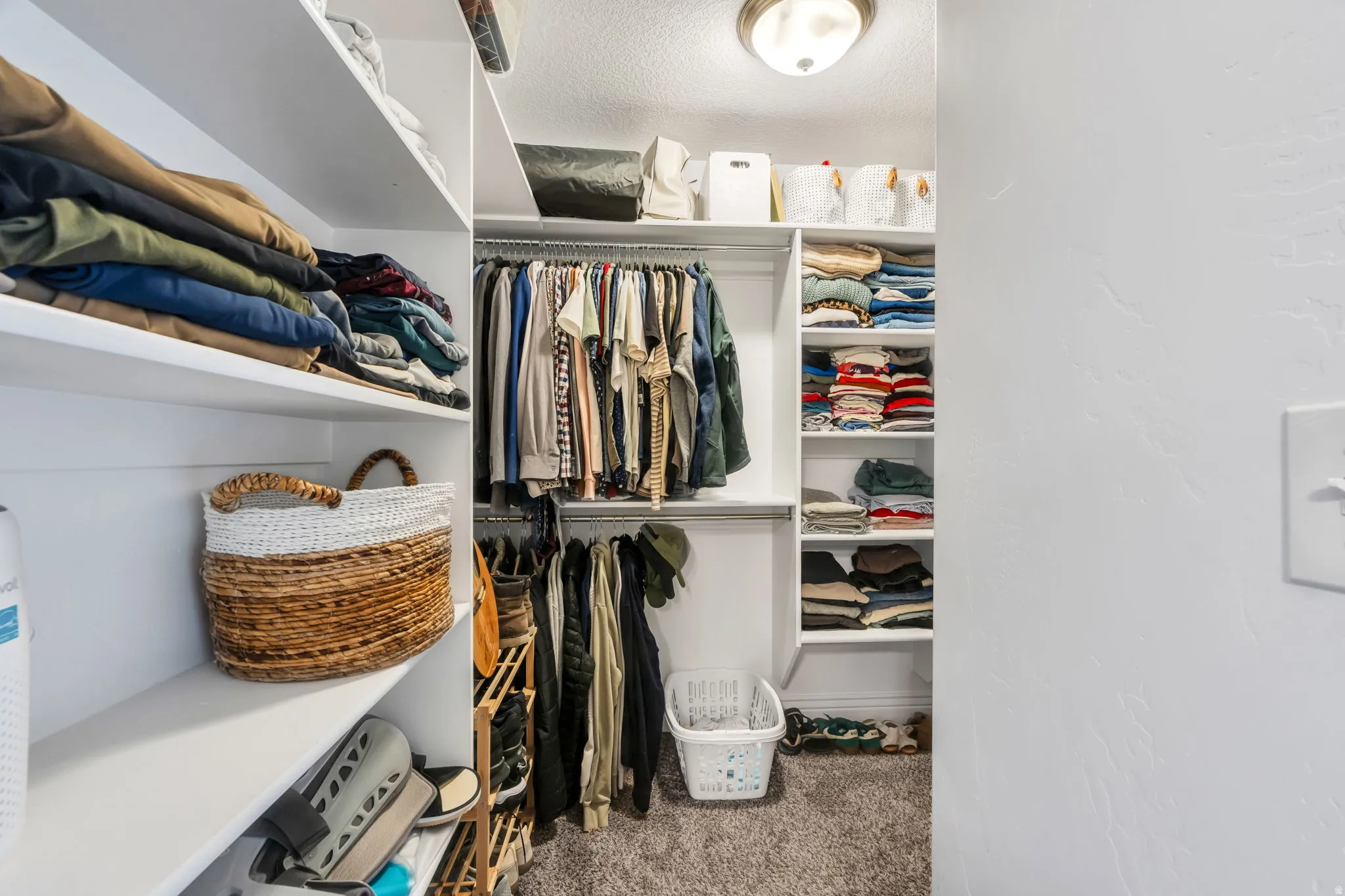 Built-in closet system with multiple shelving units and hanging rods, complemented by carpet flooring and an overhead flush-mount light fixture