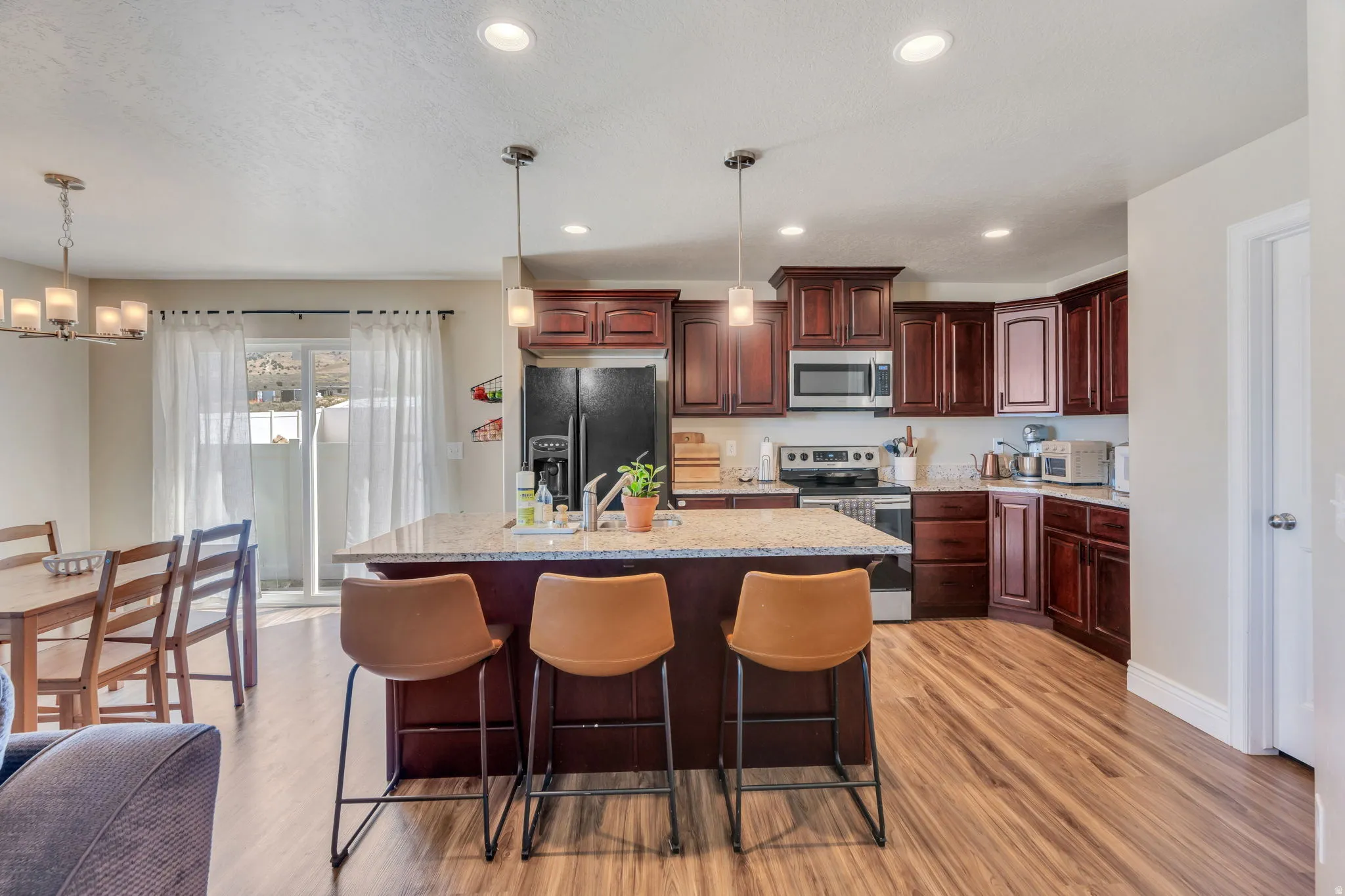 Kitchen featuring wood-finish flooring, dark wood cabinetry, stainless steel appliances, and a central island with a light-colored countertop