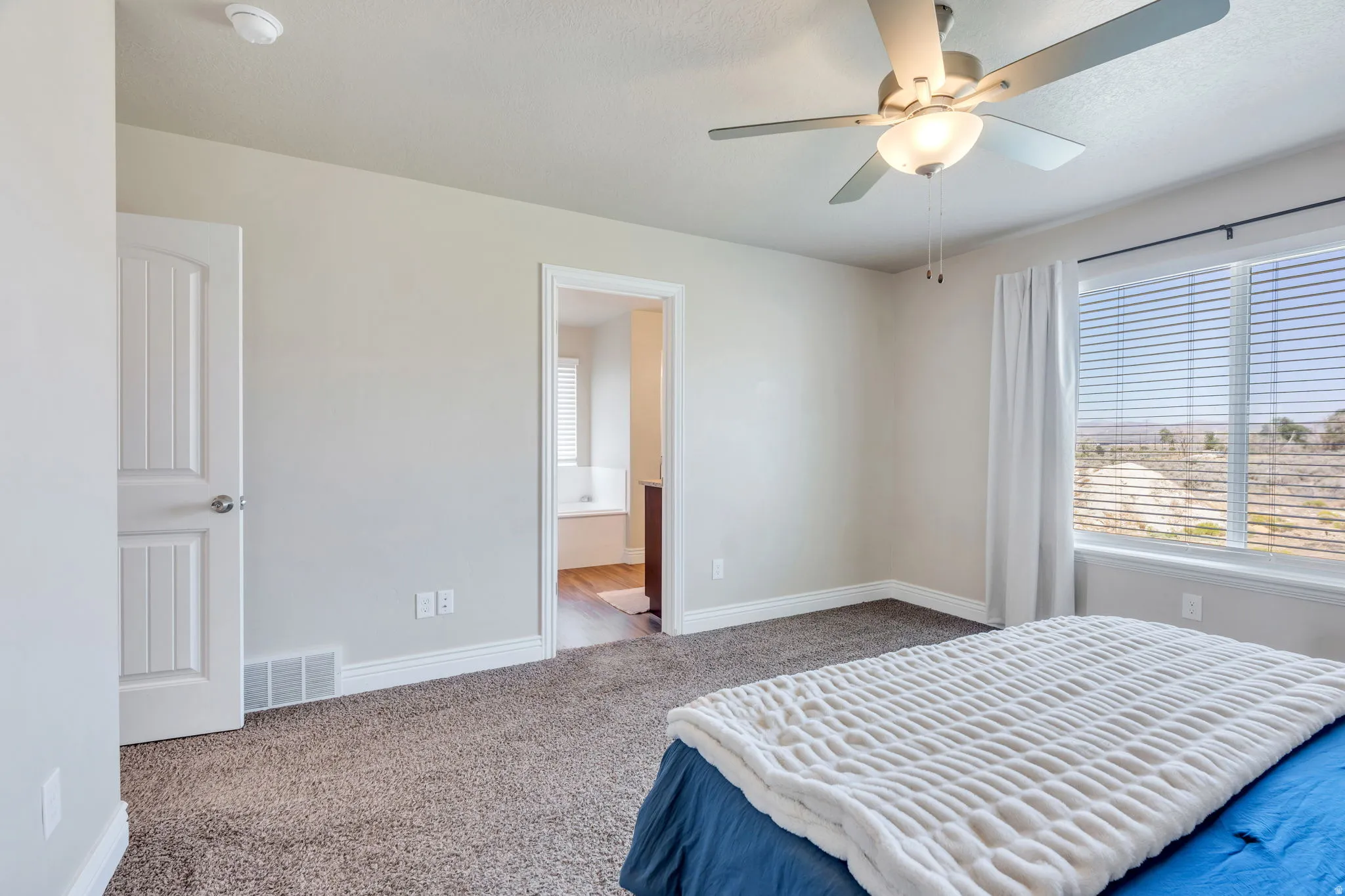 Carpeted flooring, ceiling fan with integrated lighting, white trim, white paneled doors, and a large window with blinds
