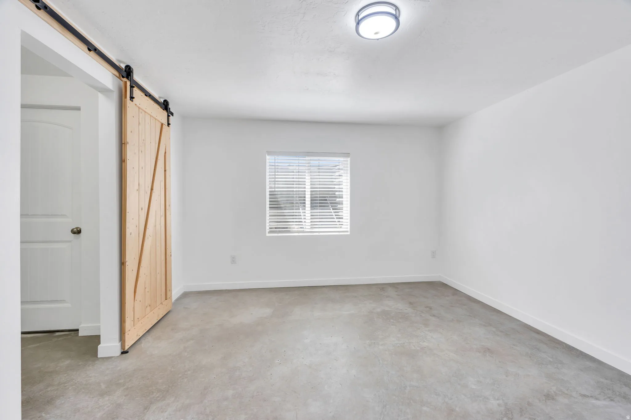 Neutral-toned carpeting, a window with horizontal blinds, and a built-in flush mount light fixture