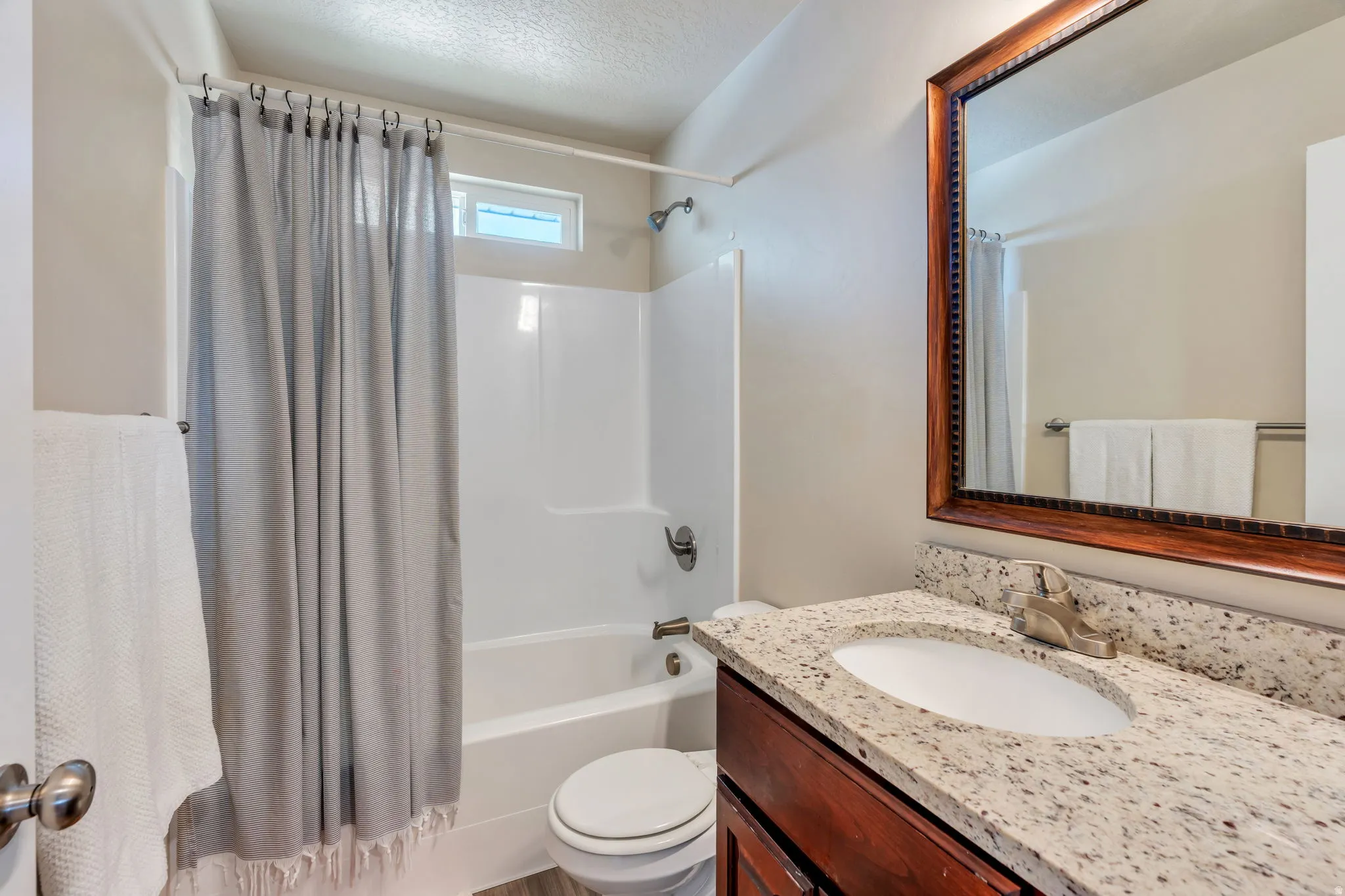 Bathroom featuring a wood-finish vanity, light-toned countertop, integrated sink, and a framed mirror