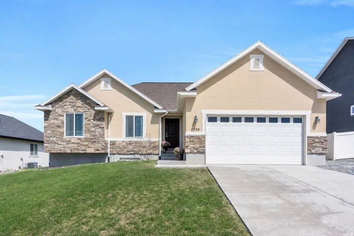 Stucco exterior with stone accents, a two-car garage, concrete driveway, and a front entry