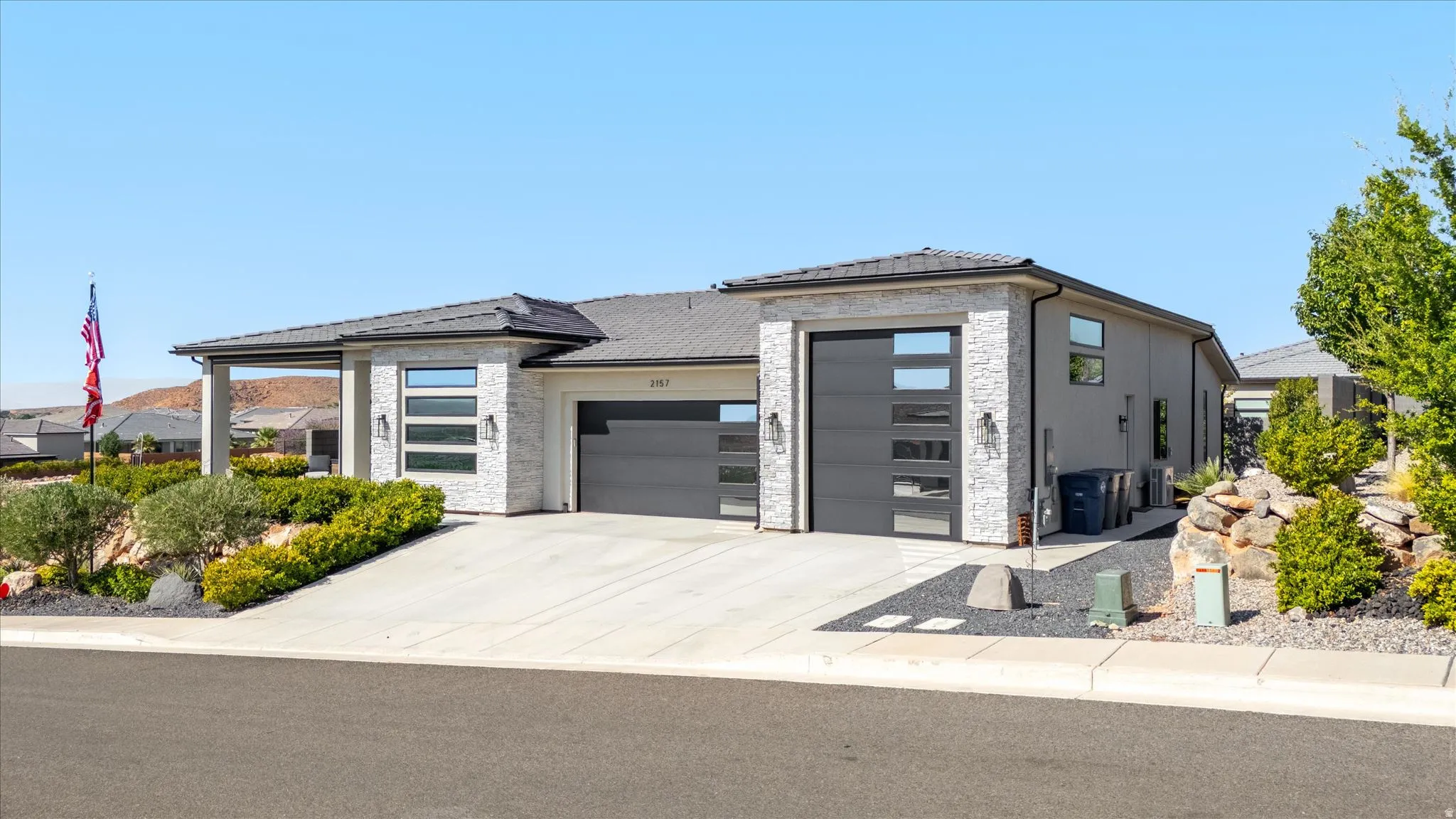 Contemporary exterior with stone facade accents and dark gray garage doors