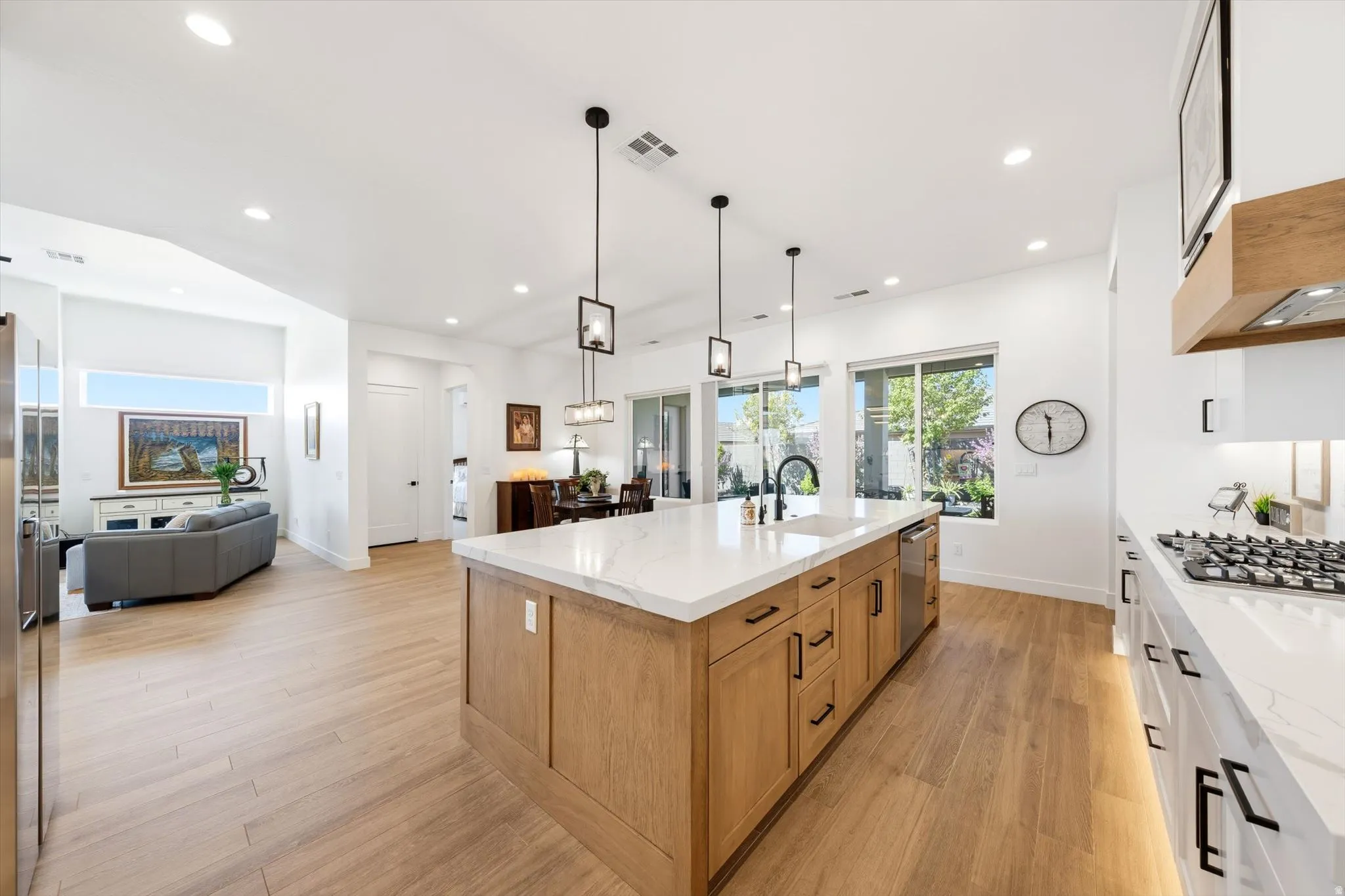 Expansive kitchen island with a built-in sink, stainless steel dishwasher, and pendant lighting