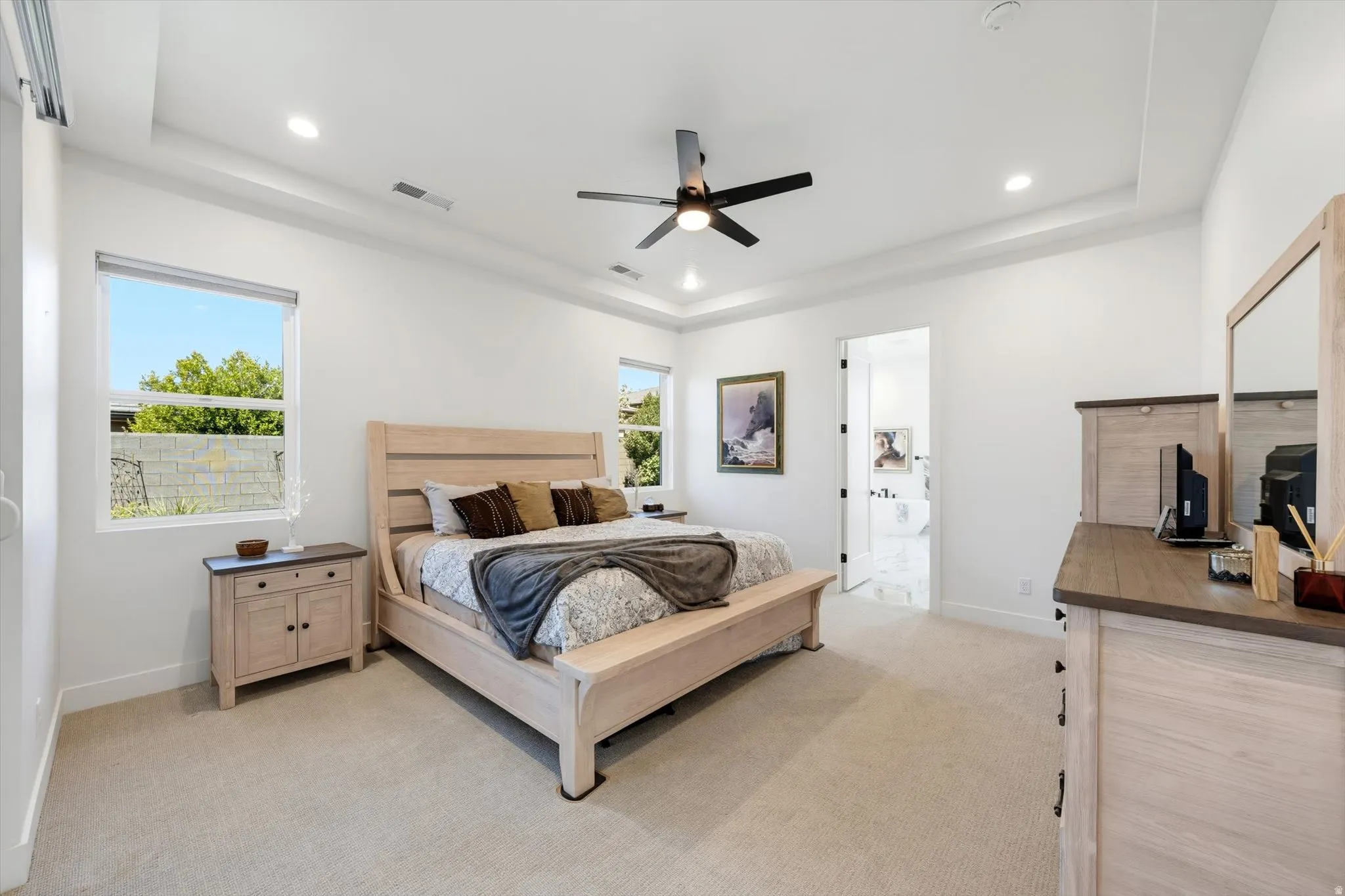Recessed lighting, ceiling fan, tray ceiling, carpeted flooring, and natural light from multiple windows