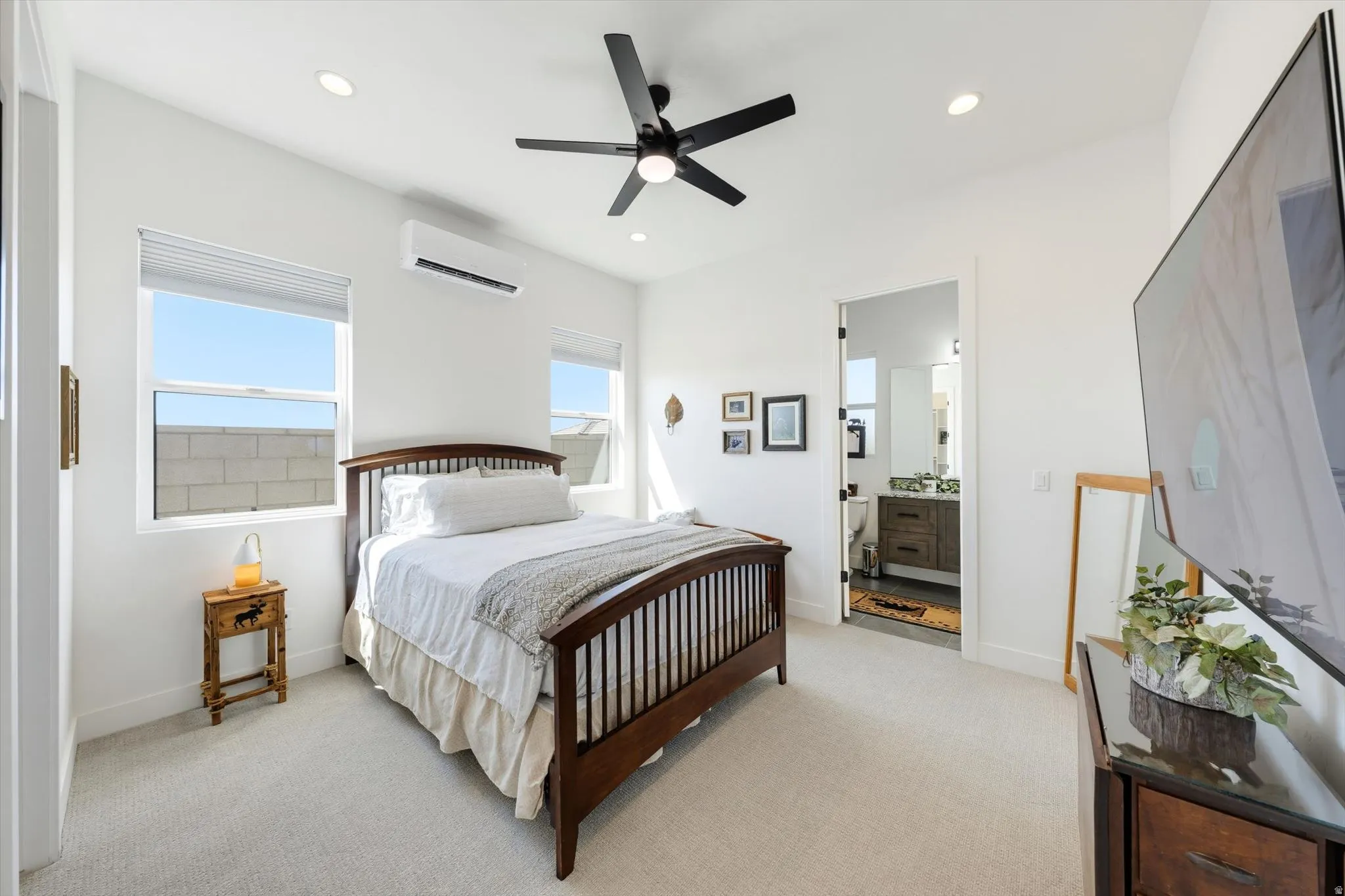 Recessed lighting, ceiling fan, wall-mounted air conditioning unit, white walls, and light-colored carpeting