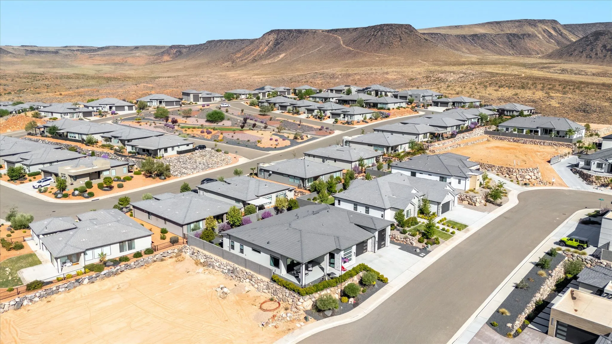 Contemporary residential development featuring single-story homes with dark gray roofs and desert landscaping