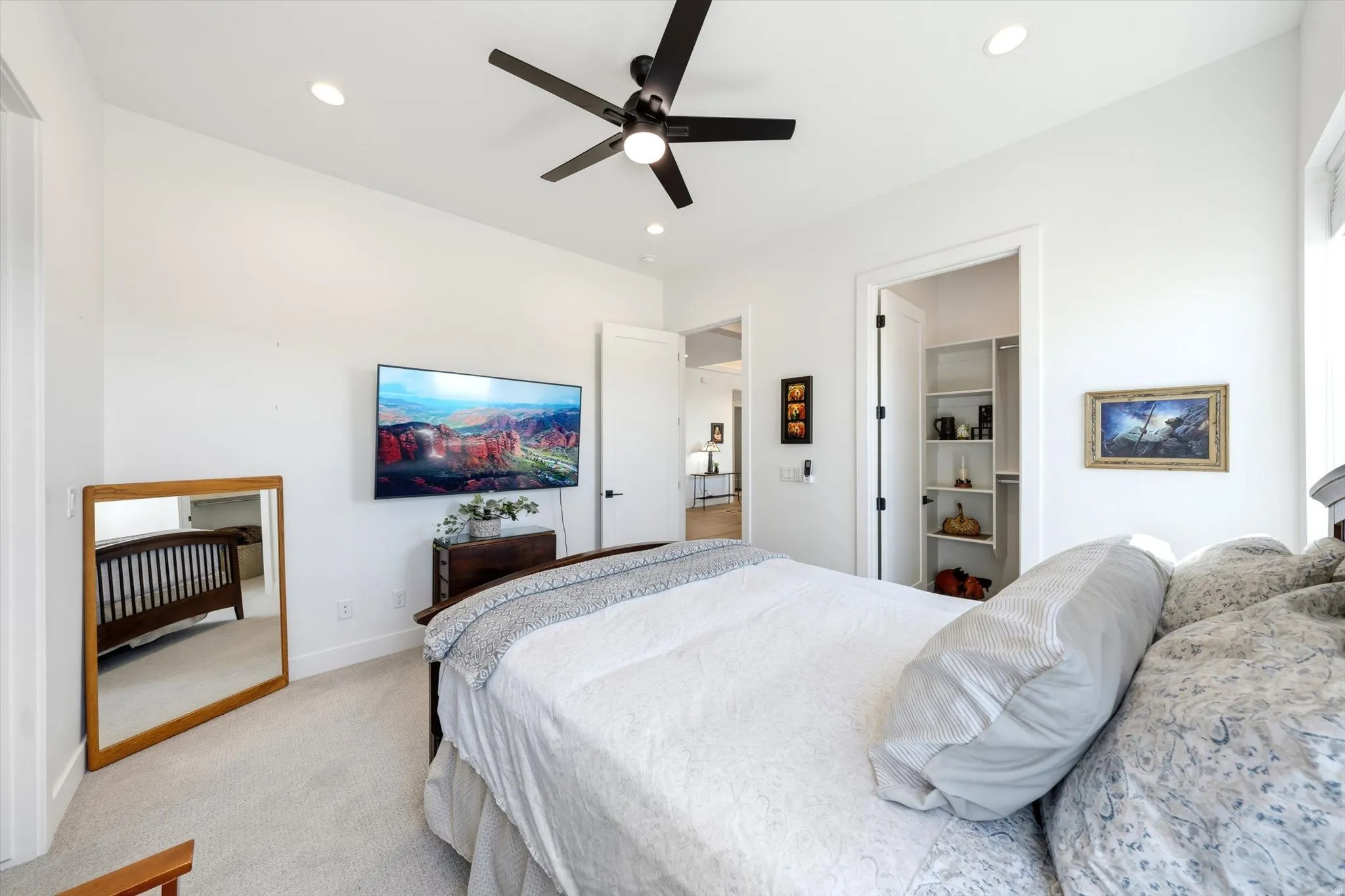 Spacious primary bedroom featuring recessed ceiling lighting, a modern ceiling fan with dark finish, and carpet flooring