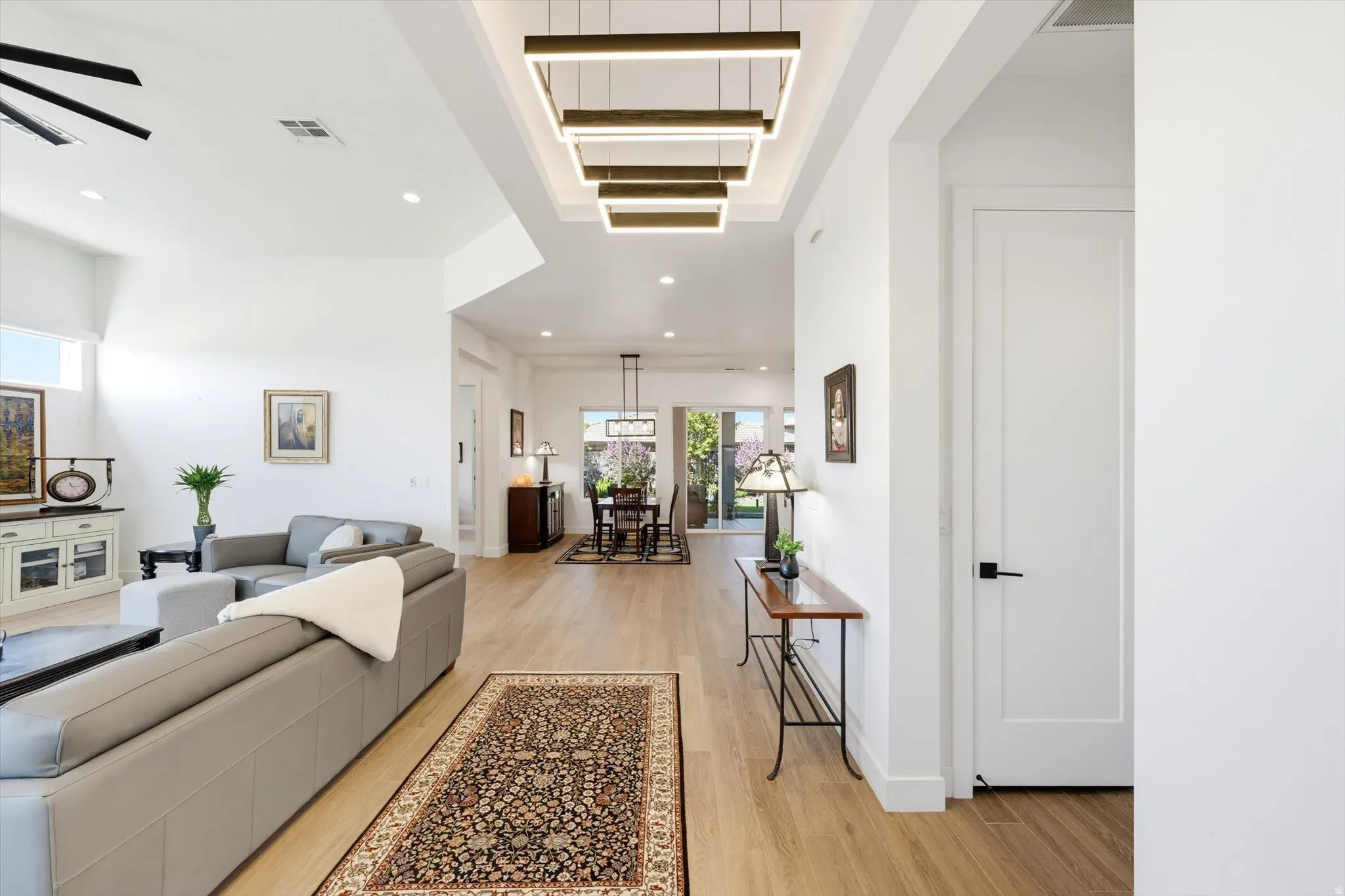 High ceilings, recessed lighting, wood-finish flooring, white walls, and contemporary linear light fixtures